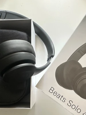 Beats Solo trådlösa hörlurar svart - Snygga svarta Beats Solo on-ear hörlurar med stilren design och mjuka öronkuddar. Trådlös Bluetooth-anslutning och justerbar huvudbygel. Perfekta för musik, gaming eller videos. Levereras med matchande fodral.
