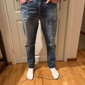 Blå selvege jeans från nudie - Säljer ett par blå selvege jeans från nudie med snygga slitningar och tvättade detaljer. Jeansen är iprincip nya och fräscha. Hör av er vid frågor