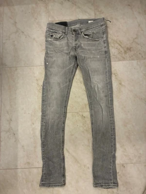 Grå skinny jeans med slitningar - Gråa jeans från dondup. Jeansen är i okej skick då dem har lite små hål och slitningar men inget som man tänker på. Sedan har dem en lagning vid insidan av låret men inget som syns vid användning. Där av billigt pris. Strlk 30. Hör av er vid frågor!