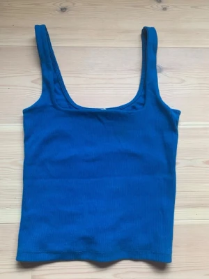 Blå ribbad linnetopp från Zara - Snygg blå ribbad linnetopp från Zara med breda axelband och rundad halsringning. Perfekt att styla med jeans eller kjol för en trendig look. Materialet är stretchigt och sitter skönt mot kroppen.