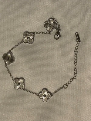Van cleef armband  - Snyggt armband i silverfärg med fem blommiga länkar. Varje blomma har en räfflad yta och små pärldetaljer runt kanterna. Kedjan är tunn och har ett klassiskt klospänne. Perfekt för dig som gillar stilrena och trendiga accessoarer. Silver 925