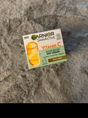 Garnier Glow Boost Dagkräm Vitamin C - Glow Boost Day Cream från Garnier SkinActive med Vitamin C och citrus. Krämen är framtagen för att ge lyster, jämna ut hudtonen och återfukta trött och glåmig hud. Förpackningen är vit med inslag av orange och grönt. Passar för daglig hudvård.