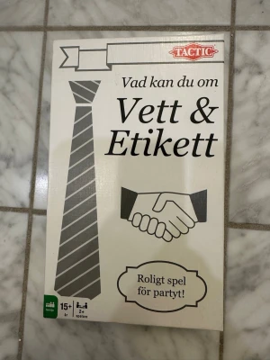 Sällskapsspel Vett & Etikett Tactic - Sällskapsspelet 'Vad kan du om Vett & Etikett' från Tactic är ett roligt frågespel för 2 eller fler spelare, rekommenderat från 15 år. Spelet kommer i en vit kartong med svart och grå design, inklusive tärning, kort, penna och timglas.