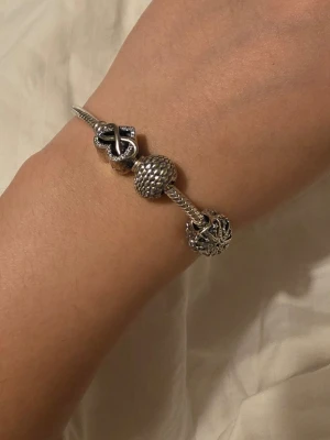 Pandora armband  - Säljer min Pandora silver armband med två berlocker en från Game of Thrones och  en med stjärnor i storlek 16