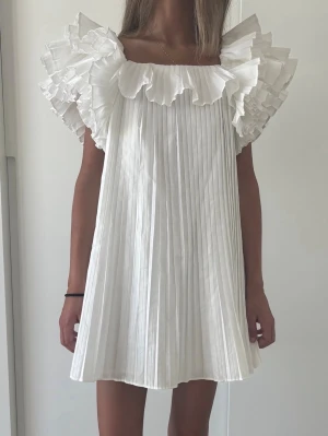 Vit plisserad klänning med volang - Populär och eftertraktad klänning från Zara! 💓💓 perfekt till student eller liknande! 