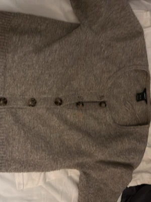 Grå kofta med knappar från H&M - Mysig grå kofta från H&M med stora knappar framtill och ribbade muddar. Perfekt att slänga på sig när det är kyligt ute.☺️