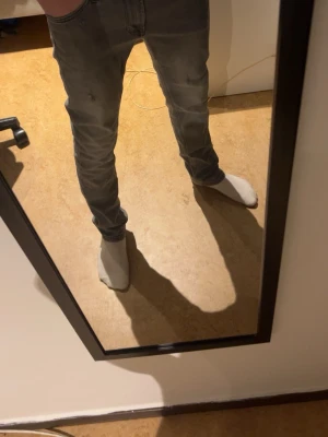 Grå slim fit jeans herr - Säljer ett par grå slim fit jeans med klassisk femficksdesign och normal midja. Jeansen har en snygg tvättad look och smal passform som sitter tajt längs benen. Perfekta för dig som gillar en modern och enkel stil.