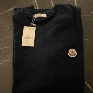 Marinblå Moncler t-shirt Strl M -  Moncler Tshirt Strl M Marinblå, aldrig använd inga slitage eller liknande. Väldigt fin och fräsch!   Finns i Stockholm, kan mötas upp samt fraktas!