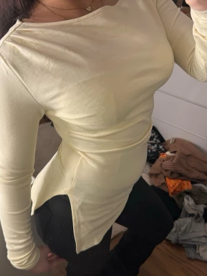 Ljusgul långärmad topp - Snygg ljusgul långärmad topp med rund halsringning och figurnära passform. Toppen har en enkel och clean design utan synliga detaljer, perfekt att styla med olika accessoarer. Materialet känns mjukt och stretchigt.
