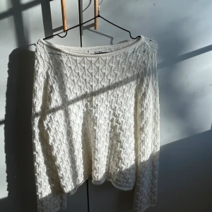 Vit stickad tröja med spetsdetaljer - Supersöt vit tröja i stickat material med fina spetsdetaljer och ett diskret mönster. Kjolen har en mjuk och bekväm passform.