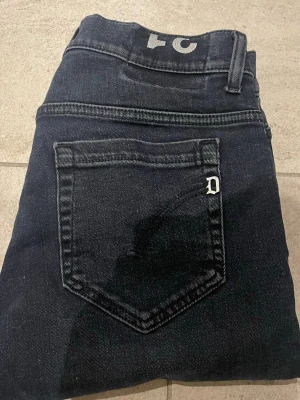 Mörkblå slim fit jeans från dondup - Snygga mörkblå slim fit jeans från Dondup med klassisk femficksdesign och diskret D-logga på bakfickan. Jeansen har raka ben och är tillverkade i mjukt denimtyg som ger en skön passform. Perfekta för dig som gillar stilrena och tidlösa jeans.