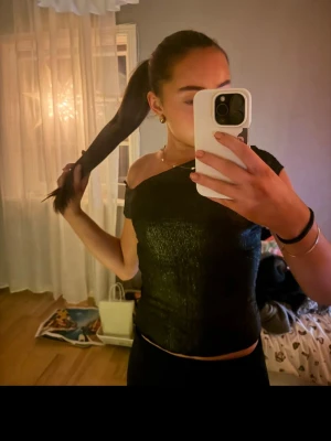 Glittrig svart offshoulder topp H&M - ALDRIG ANVÖND LAPP KVAR.                         Säljer en svart glittrig topp från H&M med offshoulder-design och korta ärmar. Toppen är croppad och har en smockad, stretchig struktur.