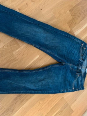 Mörkblå raka herr jeans - Säljer ett par klassiska mörkblå herr jeans med rak passform och fem fickor. Jeansen har normal midja, bälteshällor och snygga kontrastsömmar. Perfekta till en avslappnad stil och tillverkade i slitstark denim.