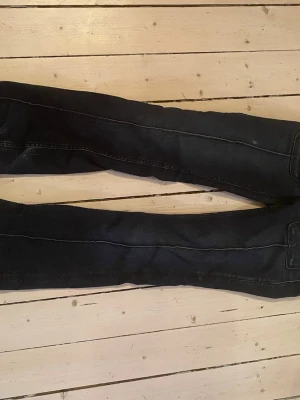 Svarta  jeans med söm - Säljer ett par svarta  jeans med markerad söm längs benen. Jeansen har en smal passform och klassisk femficksdesign. Perfekta för dig som gillar en stilren och enkel look.