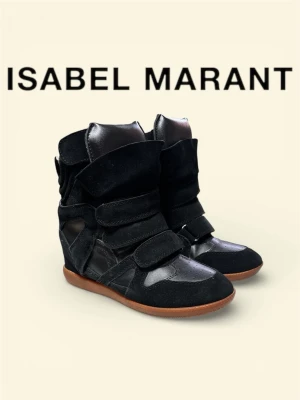 Isabel Marant svarta sneakers med kilklack - Svarta sneakers från Isabel Marant med kilklack och kardborreband. Skorna har en cool design i mocka och läderdetaljer samt en brun gummisula. Perfekta för dig som vill ha en edgy och trendig look. Har dock ingen box kvar så lite minus men annars är allt i jätte bra skick:)