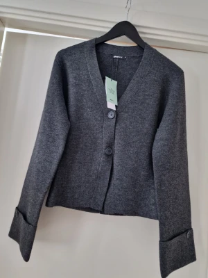 Gina Tricot mörkgrå kofta med stora knappar XS - OBS, jag kan fixa fri frakt, kontakta mig innan köp. Stilren mörkgrå kofta från Gina Tricot med två stora knappar framtill och breda uppvikta ärmslut. Koftan har en rak passform, V-ringning och är tillverkad i mjukt stickat material. Perfekt för lager på lager och enkel att matcha. Storlek XS