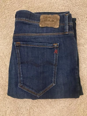 Replay  jeans mörkblå W30 L34 - Mörkblå skinny jeans från Replay med klassisk femficksdesign och snygga kontrastsömmar. Modellen har normal passform i midjan och är tillverkad i slitstarkt jeansmaterial. Perfekt för dig som gillar en smal siluett och stilren look.