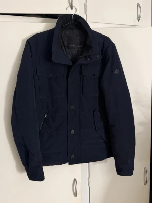 J.Lindeberg jacka - Säljer nu en J.Lindeberg jacka som är i riktigt schysst skick. Snygg marinblå färg med den klassiska loggan på vänstra armen. Storlek M! Hör av er🤝