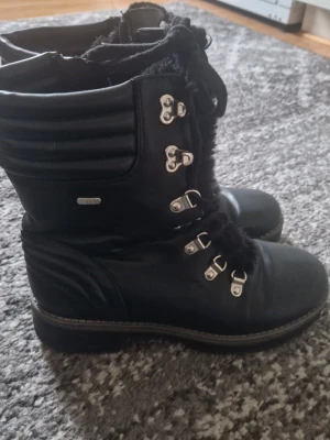 Svarta vinterstövlar från Esprit - Svarta stövlar från Esprit med grov sula, snörning och vadderade detaljer vid skaftet. Metallhakar för snörningen och mjukt foder på insidan. Perfekta för kalla dagar och har en cool, sportig look.