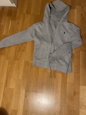Grå hoodie från Ralph Lauren - Säljer nu denna polo ralph lauren zip hoodien eftersom att den är för liten för mig, passar S bra men XS kan även fungera, finns inga defekter jag har märkt alls som hål eller sådant, vid frågor eller mer specifika bilder är det bara o höra av sig!