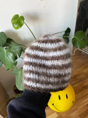 Randig fluffig mössa i ullmix - Virkad ljusblå och brun randig mössa – unisex vuxenstorlek  Handvirkad mössa i ljusblått och brunt. Gjord i ull-, mohair- och akrylmix som ger en mjuk och borstad look. Varm och bekväm, perfekt till höst och vinter.  Material: ull / mohair / akryl Storlek: unisex vuxen  Passar till y2k, streetwear och vardagsstil.  #virkad #handvirkad #randigmössa #unisex #vuxenstorlek #mohair #ullmössa #ljusblå #brun