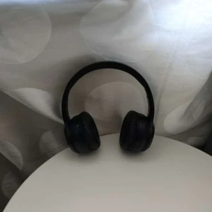 Svarta over-ear hörlurar - Snygga svarta over-ear hörlurar med vadderade öronkuddar och justerbart huvudband. Sladdlös design och stilren look som passar perfekt till musik, gaming eller videos. Tillverkade i plast och konstläder för en bekväm känsla.