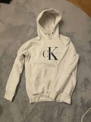 Vit hoodie från Calvin Klein  - Snygg vit hoodie från Calvin Klein med stor CK-logga på bröstet. Använd några gånger, jätte skön att ha på sig. 
