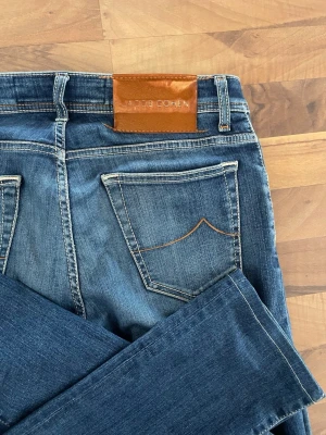 Jacob Cohën jeans - Snygga och exklusiva jeans från Jacob Cohën, modell NICK, i en stilren blå nyans. Kända för sin premiumkvalitet, bekväma passform och lyxiga detaljer. Ett perfekt val för dig som vill kombinera elegans med vardagsstil. 	•	Storlek: W32 	•	Modell: NICK 	•	Färg: Blå 	•	Skick: Mycket bra  Detaljer: ✔️ Tillverkade i högkvalitativ denim ✔️ Bekväma med exklusiv känsla ✔️ Klassisk och tidlös modell som funkar både upp- och nedklätt  Mått (se bild): A: 41.5cm B: 24cm C: 34cm D: 23cm E: 19cm F: 17cm G: 70cm 