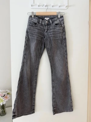 Grå bootcut jeans med detaljer - Snygga grå bootcut jeans med broderade detaljer på fickorna och dekorativa bakfickor med knappar.