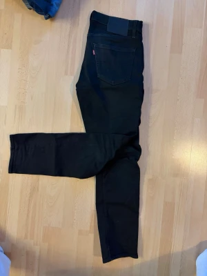 Levi’s 511 slim fit - Säljer ett par svarta slim fit jeans med klassisk femficksdesign och raka ben. Jeansen har en diskret röd etikett på bakfickan och silverfärgade nitar framtill. Perfekta för dig som gillar en clean och stilren look. W31 L32. Riktigt feta