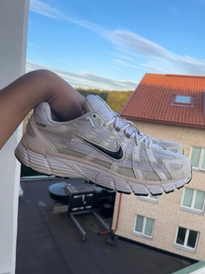 Nike P-6000  - Nike P-6000 sneakers i vitt och beige med mesh och syntetiska paneler. Skorna har en chunky sula, svarta detaljer och klassisk Nike Swoosh på sidan. Perfekta för en sportig och trendig look.