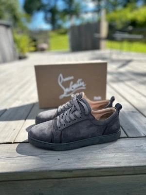 Christian Louboutin Skor Grå - Gråa Christian Louboutin skor i storlek 42, Använt skick och tyvärr hål i hälen på höger sko och ganska slitet på vänster men inget hål, Sko boxen medföljer. Har ni någon fundering kring skorna skicka till mig☺️