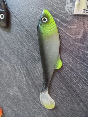Grön och svart jiggfisk - En mjuk jiggfisk i grönt och svart med realistiskt öga och paddelstjärt. Perfekt för fiske efter rovfisk. Kroppen har en övergång från limegrönt till svart och en liten gul detalj vid stjärtfenan. Hemmagjord 