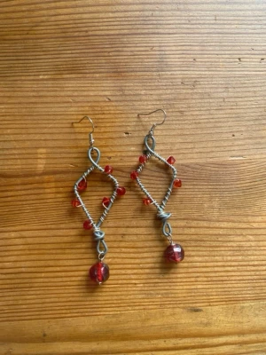 Handgjorda örhängen med röda pärlor - Mina handgjorda örhängen.  Röda pärlor på silverfärgad metalltråd.  Nickelfria!  Följ min Instagram för mer <3 @veras.smycken. Unika örhängen i silverfärgad metalltråd formade som romber, dekorerade med små röda pärlor längs kanterna och en större röd pärla längst ner. Perfekta för dig som gillar statement-smycken och vill sticka ut med en kreativ stil.