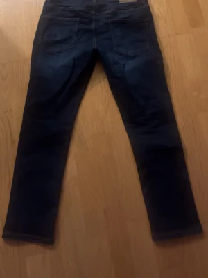 Mörkblå raka jeans - Storlek W30 L30Säljer ett par mörkblå jeans med rak passform och klassisk femficksdesign. Jeansen har tydliga sömmar och är tillverkade i denim. Perfekta för dig som gillar en enkel och stilren look.