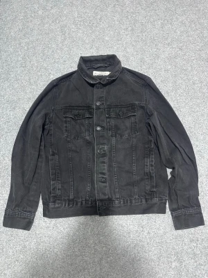 Svart jeansjacka från H&M L.O.G.G. - Stilren svart jeansjacka från H&M:s L.O.G.G.-kollektion. Klassisk modell med två bröstfickor med lock och knappar framtill. Snygg krage och raka ärmar. Perfekt för dig som gillar en enkel men trendig look.