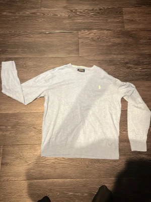 Ljusblå tröja från Polo Ralph Lauren - Ljusblå långärmad tröja från Polo Ralph Lauren med rund halsringning och den klassiska broderade loggan i vitt på bröstet. Tröjan har ribbade muddar vid ärmslut och nederkant. Perfekt för en clean och stilren look.
