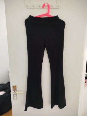 Svarta ribbade bootcut leggings - Säljer ett par svarta leggings med ribbad struktur och bootcut-ben. De är stretchiga och har hög midja för en bekväm passform. Perfekta till en avslappnad look och passar till många olika stilar. Vet tyvärr inte storlek eller märke då lappen är borttagen. 