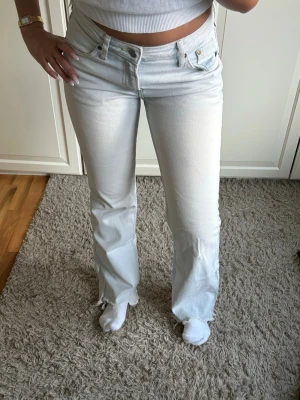 Ljusblå bootcut jeans - Säljer ett par ljusblå bootcut jeans och klassiska fem fickor. Jeansen har råa kanter vid bensluten och är tillverkade i ett mjukt denimtyg. Perfekta för en avslappnad och trendig look.