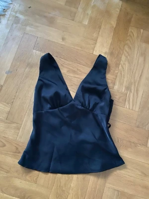 Svart satintopp  - Säljer en jätte fin svart satin topp! Helt ny och oanvänd. Storlek S.