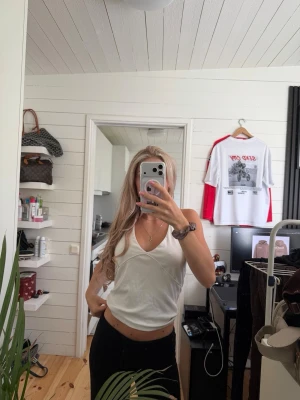 Vit v-ringad linnetopp - Snygg vit linnetopp med v-ringning och smala axelband. Toppen är croppad och har en enkel, stilren design som passar perfekt till jeans eller kjol. Perfekt för varma dagar och enkel att matcha med olika outfits.