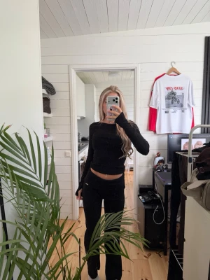 Svart ribbat loungewear-set aimn  - Säljer ett svart ribbat loungewear-set med långärmad topp och matchande byxor. Setet har en tight passform och små metalltaggar som detalj på både tröjan och byxan. 