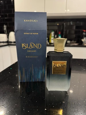 Khadlaj island dreams - Island Dreams från Khadlaj är en exklusiv parfym i en elegant svart och guld flaska med texturerad yta och guldfärgad kork. Förpackningen är mörkblå med guldiga detaljer och ger en lyxig känsla. Perfekt för dig som vill sticka ut med en unik doft.