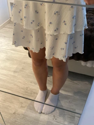 Blommig volangkjol - Supersöt kort kjol i ljusgul nyans med små blå blommor. Kjolen har dubbla volanger och vågig kant. Bara att fråga om ni undrar nått och kom gärna med prisförslag!💕🫶🏼
