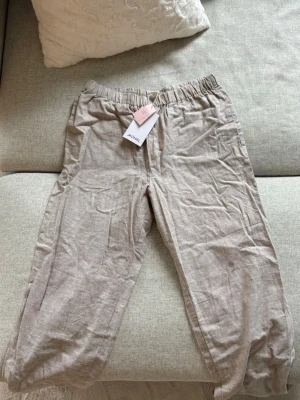 Beige linnebyxor  - Snygga beige linnebyxor från Monki med avslappnad passform och resår i midjan. Nyskick med lappen kvar. 