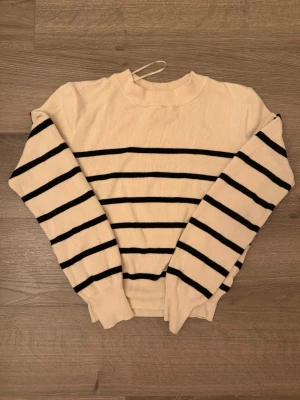 Randig stickad tröja från H&M XS - Krämvit stickad tröja från H&M med svarta horisontella ränder. Tröjan har rund halsringning, långa ärmar och ribbade muddar vid ärmslut och nederkant. Väldigt skön, inga synliga defekter!