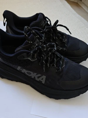 Svarta Hoka sneakers med Gore-Tex ATR 7  CHALLENGER 41,5 - Snygga svarta sneakers från Hoka med Gore-Tex Invisible Fit som håller fötterna torra. Skorna har en chunky sula, mesh- och syntetmaterial samt Hoka-logga på sidan. Perfekta för dig som vill ha både stil och funktion i vardagen.  Från Rökfritt, djurfritt och Alkoholfritt hem .