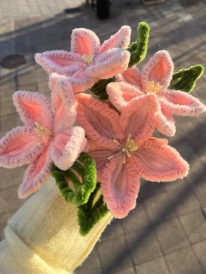 Bukett med rosa piprensarblommor - Handgjord bukett med fem stora blommor i ljusrosa och vitt, skapade av mjuka piprensare. Blommorna har detaljerade ståndare och gröna blad, vilket ger ett lekfullt och färgglatt intryck. Perfekt som dekoration eller present till någon som gillar unika hantverk.