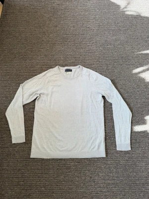 Ljusgrå stickad tröja Jack & Jones - Snygg ljusgrå stickad tröja från Jack & Jones. Tröjan har rund halsringning, långa ärmar och är tillverkad i ett mjukt, tunt material som passar perfekt till lager på lager. Enkel och stilren design som funkar till det mesta.