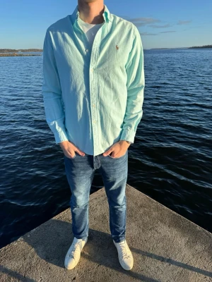Ljusblå skjorta från Ralph Lauren - Hej vi säljer nu en ljusblå skjorta från Ralph Lauren med klassisk krage och knappstängning framtill. Skick 10/10 och storlek M, vårt pris 349kr. Skjortan har lång ärm och den ikoniska broderade loggan på bröstet. Tillverkad i mjuk bomull, perfekt för en clean och stilren look.💙